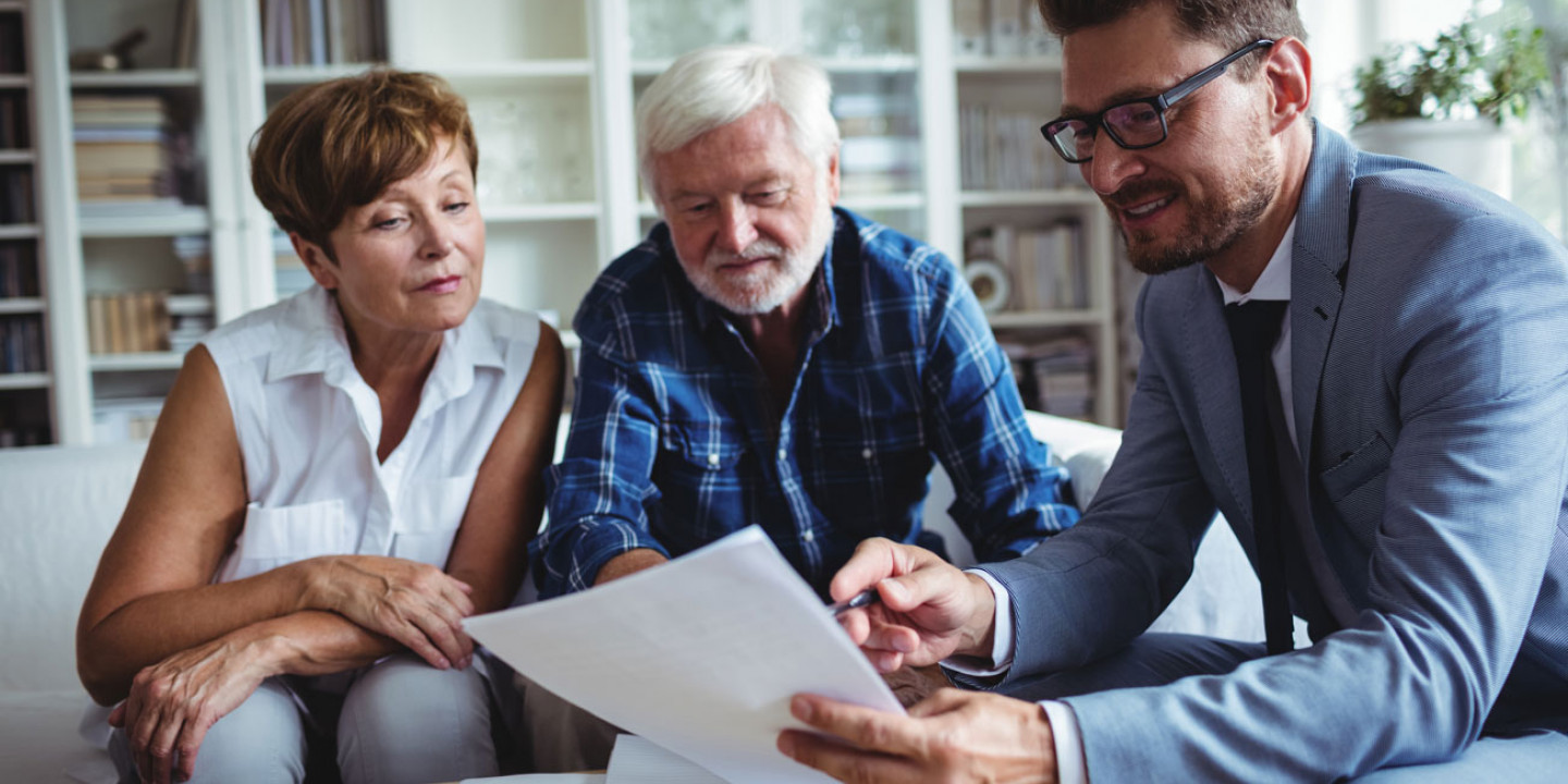 man in suit showing document to old couple on couch