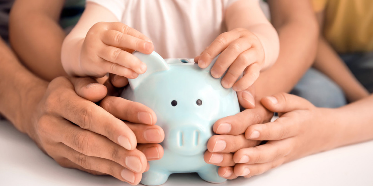 Family holding piggy bank at table
