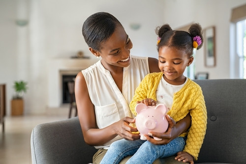 mother holding child holding piggy bank